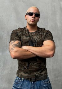 Ριγέ κοντομάνικο πουκάμισο σε καμουφλάζ σχέδιο με εφαρμοστή γραμμή. Φοριέται με μπλε τζιν παντελόνι και μια μαύρη ζώνη με καρφιά. Τα αξεσουάρ περιλαμβάνουν αλυσίδες.