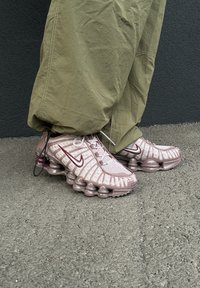Nike sportbačiai šviesiai rožinės ir bordo spalvų, su tekstūruota tinklelio viršutine dalimi ir išskirtiniu burbulų pado dizainu. Puikiai dera su laisvomis alyvuogių žalios spalvos kelnėmis.