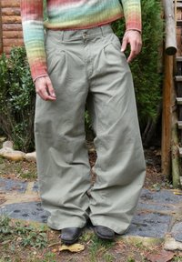 Brīvi pieguļošas khaki krāsas bikses ar augstu vidukli, krokotu priekšpusi un platiem kāju galiem. Izgatavotas no mīksta auduma, ar pogu un rāvējslēdzēja aizdari.