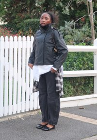 Svart skinnjacka med dubbelknäppning, vit skjorta under, svarta jeans, rutig flanellskjorta knuten runt midjan och svarta ballerinaskor.