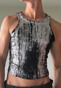 Crni i srebrni bezrukavni crop top s teksturiranim, rebrastim uzorkom i metalik završnom obradom, s kružnim izrezom i oblikovanim dizajnom.