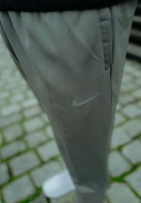 Nike srebrnasti atletski hlače imajo subtilno teksturo, elastični pas in majhen odsevni logotip na levi strani.