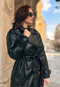 Schwarzer Leder-Trenchcoat mit tailliertem Schnitt, großen Knöpfen und geknöpften Manschetten, gekennzeichnet durch eine elegante, glatte Textur und einen übergroßen Kragen.