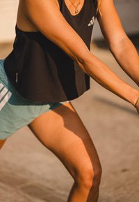 Zwarte sportieve tanktop met een losse pasvorm, gecombineerd met lichtblauwe shorts. Bevat subtiele branding en een lichtgewicht, ademend materiaal.