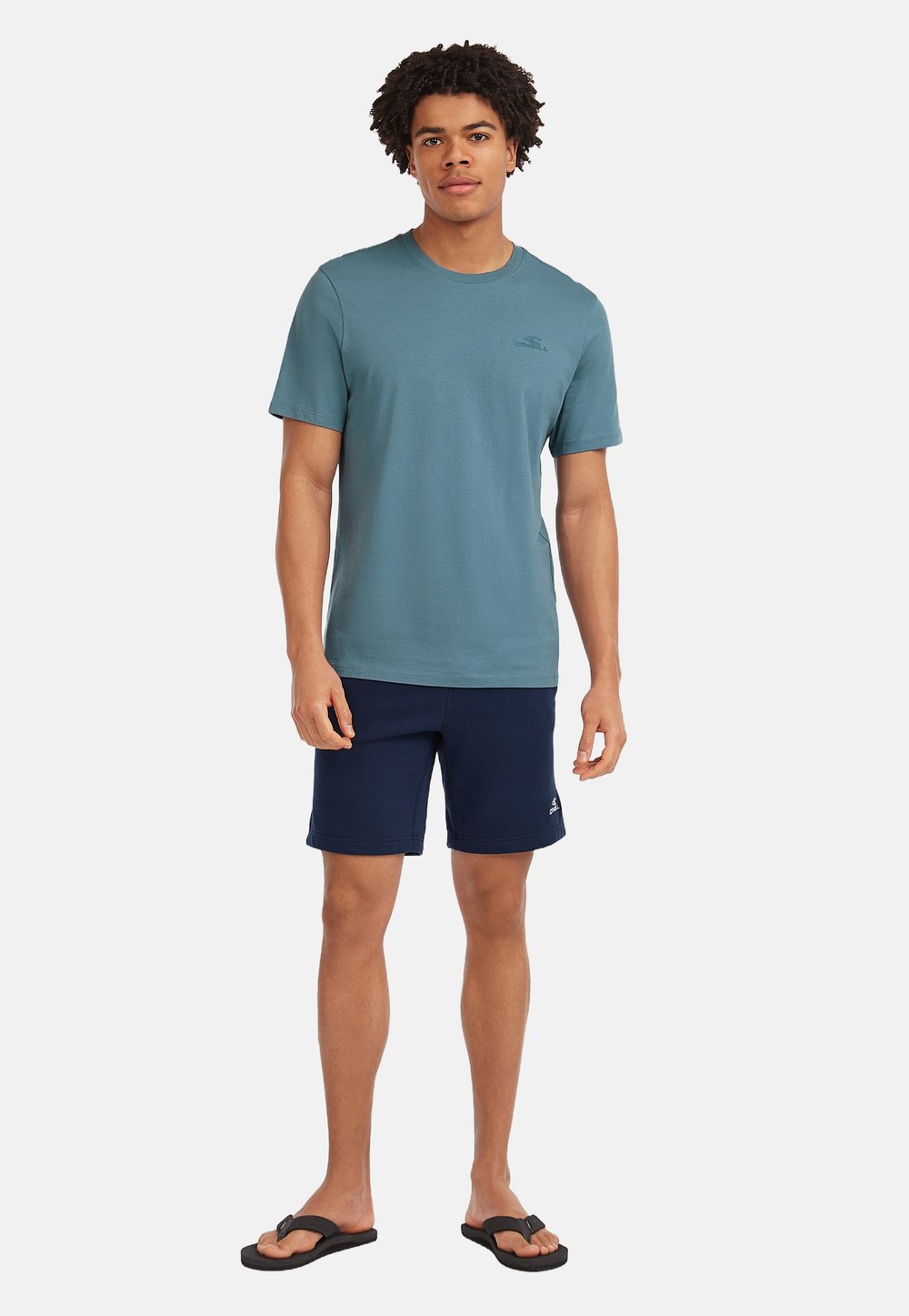 Men's teal cotton t-shirt, short sleeves, round neck; matched with navy shorts and black flip-flops. Simple logo on the t-shirt.