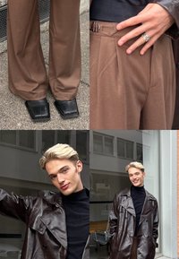 Jeune personne aux cheveux blonds courts, souriante, portant un pantalon large marron, des chaussures noires à bout carré, un col roulé noir et un manteau en cuir marron foncé.