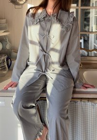 Set di pigiama a righe in blu chiaro e bianco, con colletto arricciato e lacci, pantaloni larghi e orli sfrangiati.