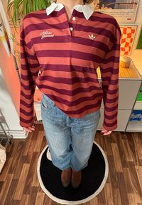 Polo-skjorte med lange ermer i burgunder og ruststripet mønster, med hvit krage, brodert med teksten "Athletic Garment" og en Adidas-logo.