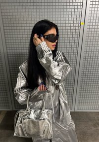 Sølvmetallic tracksuit med reflekterende tekstur og stribede accenter, parret med en matchende sølvhandtaske med lynlåslommer.