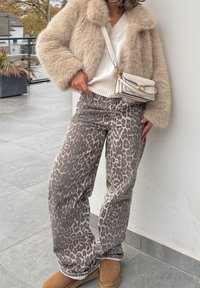 Faux fur beige coat, white knitted jumper, grey leopard print trousers, brown suede boots, and a small cream handbag with gold detailing.