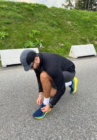 Sporta apavi tumši zilā un dzeltenā krāsā, viegla auduma un elpojoša sieta. Melna garām piedurknēm krekls, pelēki šorti un baltas zeķes.