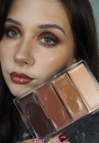 Kosmetikpalett med fire kremfarger: dyp brun, varm brun, mellomtone beige og en lys ferskenfarge. Jevn tekstur i gjennomsiktig etui.