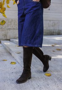 Tumed sinise teksakangaga põlvpikkused kuloodid, ees taskuga. Sobitatud pruunide seemisnahast põlveni ulatuvate saapadega, millel on madal plokkkonts ja õmbluse detailid.