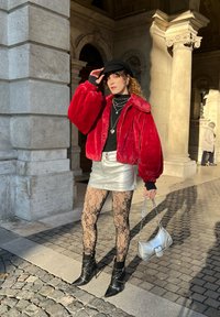 Rød faux fur-jakke med svart topp, sølvmetallic mini skjørt, sorte blonde strømpebukser og svarte naglede ankelstøvler. Sølvhåndveske.