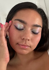 Makeuputseende med iriserende øyenskygge i blå og sølvtoner, glansfulle lepper og lys rosa neglelakk med lange negler.