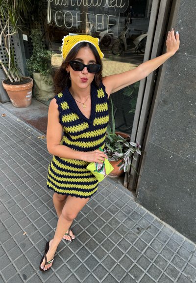 Vestido de punto sin mangas con rayas en navy y verde lima, con escote en V y dobladillo festoneado. Combinado con un sombrero amarillo y un bolso verde neón.