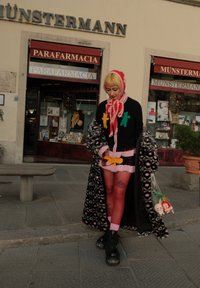 Abbigliamento colorato con maglione nero decorato con vivaci accenti di pan di zenzero, rifiniture in pelliccia rosa, calze rosse e cappotto con motivo. Accessori comprendono figurine di peluche.