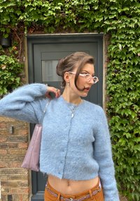 Lys blå mohair cardigan med en cropped design, rund halslinje og knappelukking. Har en myk tekstur og en avslappet passform.