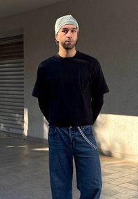 Μαύρο κοντομάνικο μπλουζάκι με στρογγυλή λαιμόκοψη, σε συνδυασμό με μπλε παντελόνι φαρδύ που διαθέτει ασημένιο αλυσίδα στη μέση.