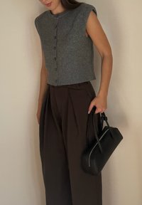 Szary, bezrękawnik, krótki kardigan na guziki, w zestawie z wysokimi brązowymi plisowanymi spodniami i czarną torebką na zamek.