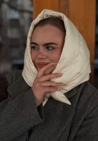 Puha krémszínű sál drapírozva egy szürke kabát felett. Hosszú körmök finom díszítéssel, texturált, stílusos megjelenést kölcsönözve.