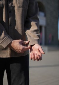 Barna gyapjúkeverék ingdzseki gombos elülső részel és két mellzsebbel. A modell a mandzsettát igazítja, bemutatva a puha textúrát és a testre szabott illeszkedést.