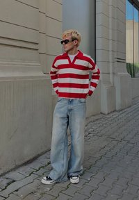 Svītrains sarkanas un baltas krāsas garām piedurknēm polo krekls, brīva piegriezuma gaiši zili džinsi, melni sporta apavi un saulesbrilles. Ikdienišķs ielu apģērbs.