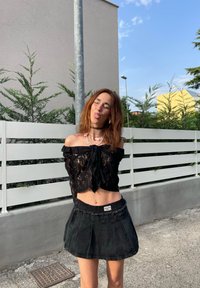 Μαύρη δαντελένια μπλούζα χωρίς ώμους με κορδόνι μπροστά, σε συνδυασμό με μαύρη υφασμάτινη μίνι φούστα με ριγέ τελείωμα και ελαστική μέση.