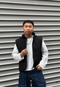 Must õmmeldud vest valge pikakarvalise särgi peal, mille juurde on kombineeritud tumedates sinistes laia säärega teksapüksid. Kaunistatud hõbedast sõrmuste ja kett-kaelakeeaga.