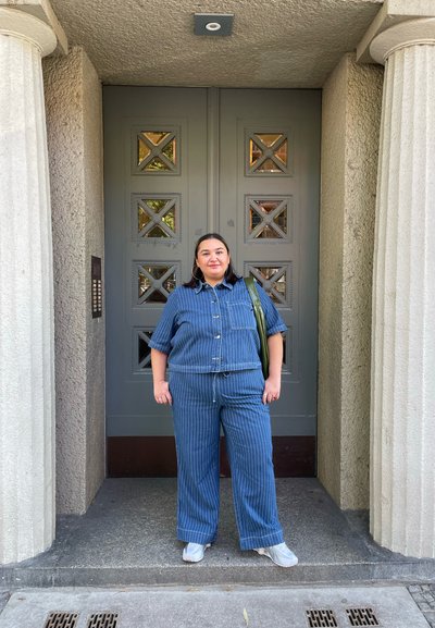 Conjunto de denim que incluye una camisa de manga corta con botones y pantalones de pierna ancha con rayas verticales. Al fondo, se observa una puerta gris texturizada.