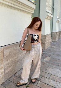 Top senza spalline a fantasia bianco e nero, pantaloni beige chiaro a gamba larga, borsa marrone e sandali scuri. Tessuti morbidi e vestibilità rilassata.