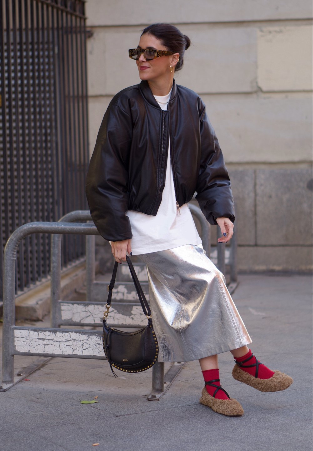 Μαύρο μπουφάν, άσπρη μπλούζα, μεταλλική ασημένια φούστα, καφέ φουσκωτά παπούτσια με κόκκινες κάλτσες, μαύρη τσάντα με χρυσές καρφίτσες, γυαλιά ηλίου.