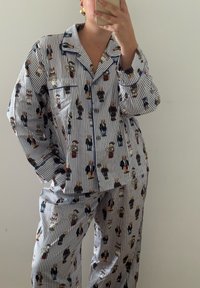 Stripete bomull pysjamassett med trykk av tegneseriefigurer. Inkluderer korte ermer, lommer og knappestolpe med kontrastfarge.