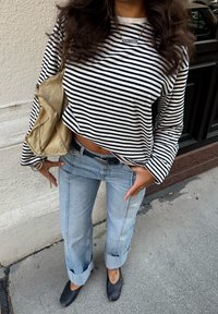 Meln-balts svītrains garām piedurknēm crop top, gaiši zili ar pagrieztām malām džinsi un melni balerīnas. Beigžu ādas soma ar saistošu detaļu.