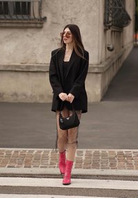 Črn blazer preko bluze s pikami, oblečen s ribjo mrežo. Rožnati gležnjarji in majhna črna torbica. Okrogla sončna očala dopolnjujejo videz.