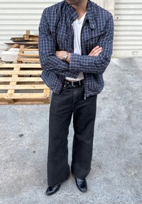 Kék kockás zakó magas gallérral, könnyű anyagból. Fekete, bő szárú farmernadrág és hegyes orrú fekete csizmák egészítik ki az öltözéket.