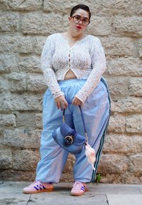Calças de treino folgadas de cor azul claro; colete de renda branco com botões; ténis cor-de-rosa; saco de denims com fechos dourados e um charm de peluche.