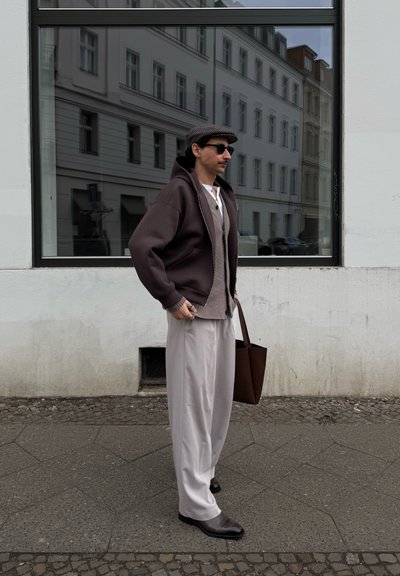 Sudadera grande de color marrón oscuro, suéter gris claro, pantalones anchos gris claro, bolso de piel marrón texturizado y zapatos marrones estampados.