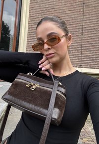 Braune Wildleder-Handtasche mit Ledeer-Akzenten, Reißverschluss und goldenen Beschlägen. Verfügt über einen kurzen Henkel und einen langen verstellbaren Trageriemen.