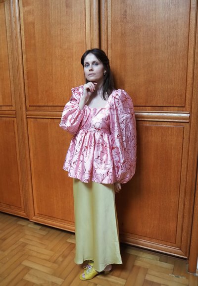 Blusa de flores rosas con mangas abullonadas, combinada con una falda larga amarilla y sandalias amarillas. Texturas suaves, cintura ajustada.