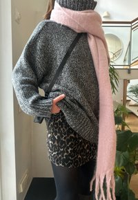 Υπερμεγέθη γκρι πλεκτό πουλόβερ, ροζ ε fringed scarf, και μια μαύρη και μπεζ λεοπάρδαλη μίνι φούστα. Μακριά μανίκια και χαλαρή εφαρμογή.