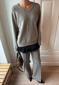 Šedý vlněný svetr s výstřihem do V p�řes černý top s krajkou, doplněný o šedé kalhoty s širokými nohavicemi a černé lodičky s špičatou špičkou. Kabelka s leopardím potiskem.