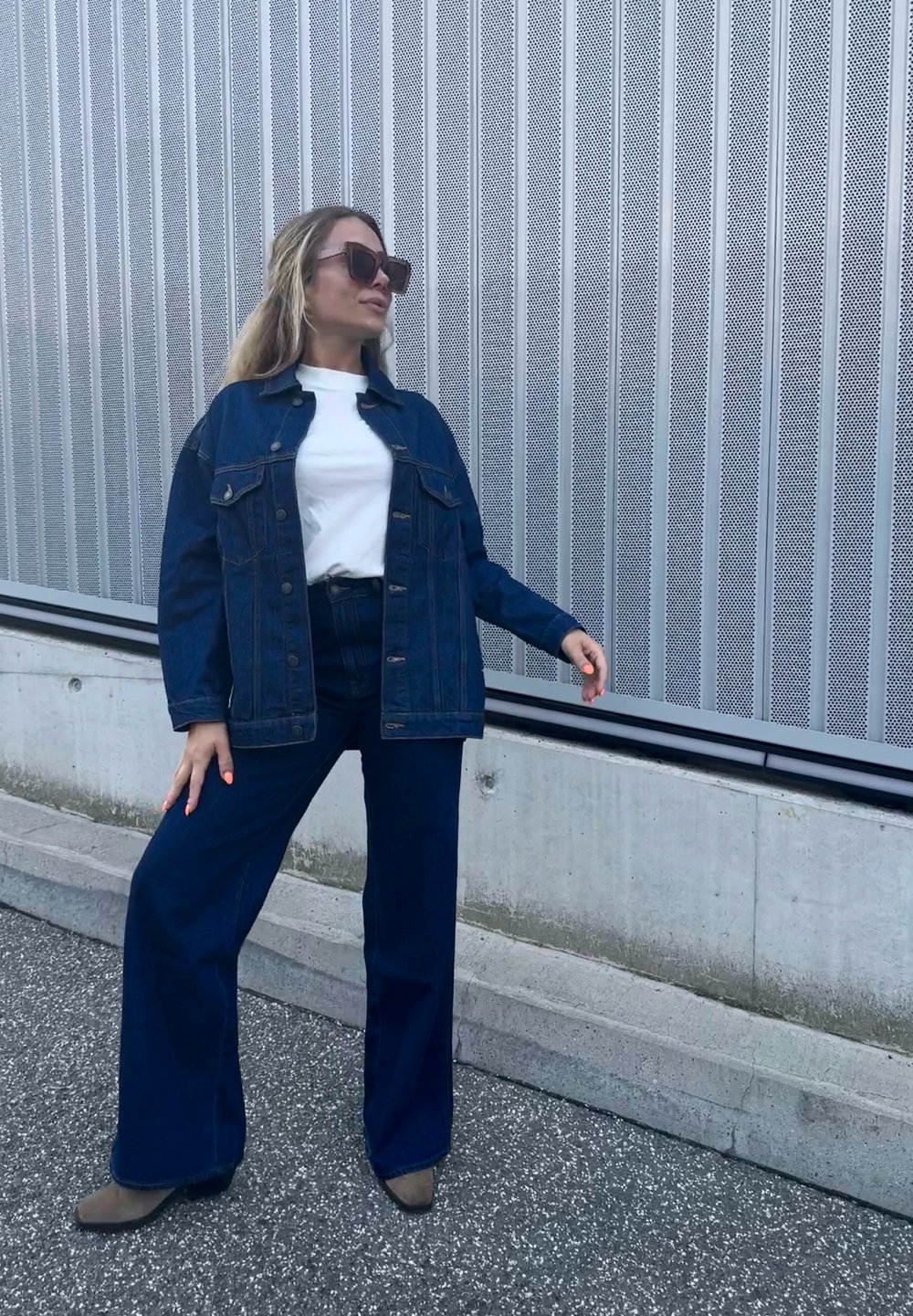 Τζάκετ από τζιν με κουμπιά μπροστά και δύο τσέπες στο στήθος, σε συνδυασμό με ψηλοκάβαλα, φαρδιά τζιν παντελόνια σε σκούρο χρώμα. Λευκό μπλουζάκι από μέσα.