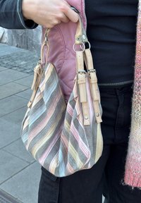 Sac à main texturé en tissu rayé multicolore, avec deux anses marron clair et des ferrures en métal. Accentué d'une doublure rose pâle et de poignées contrastantes.