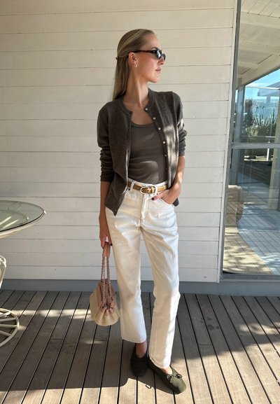 Cardigan gris, top de tirantes oliva, pantalones rectos blancos y bailarinas verde oscuro. Llevando una pequeña bolsa tejida con un lazo decorativo.