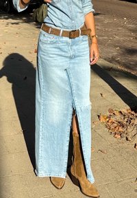 Ανοιχτό μπλε τζην μάξι φούστα με μπροστινή σχισμή, φθαρμένο στρίφωμα, συνδυασμένη με καφέ σουέτ μποτάκια μέχρι τον αστράγαλο και καφέ ζώνη.