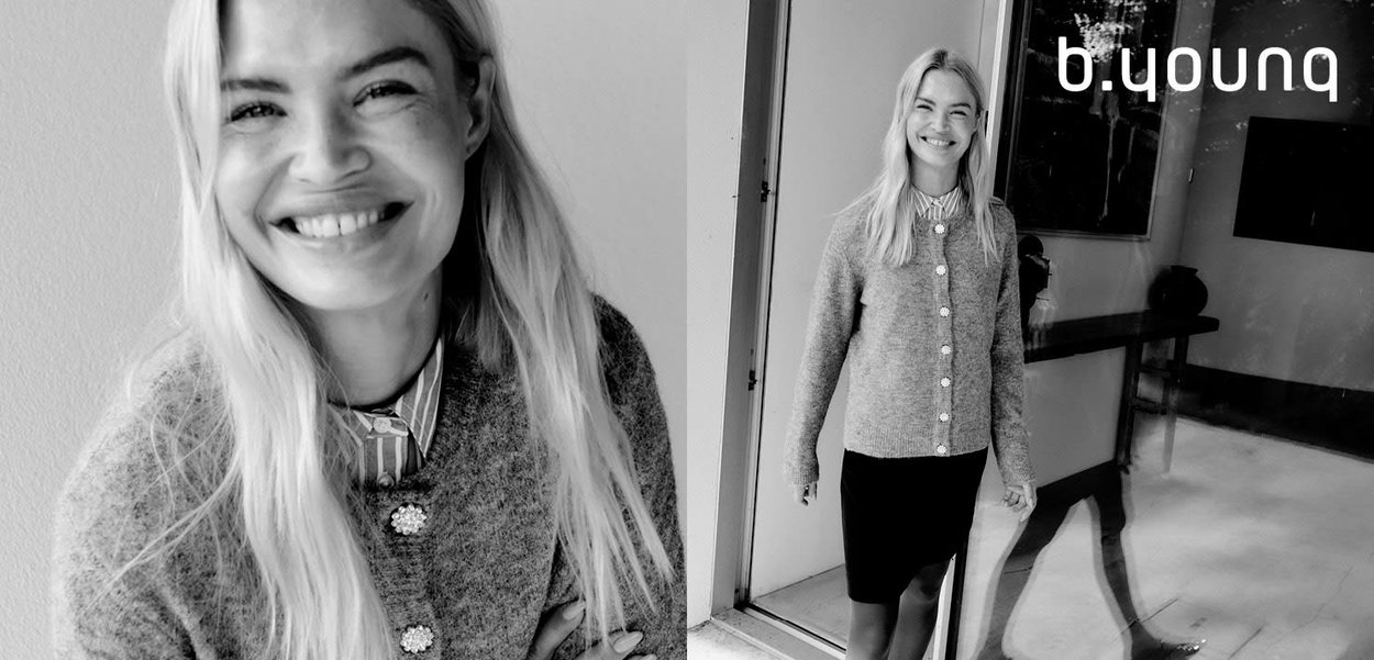 Gray knitted cardigan with decorative buttons, layered over a collared shirt and paired with a black pencil skirt. Background is minimalistic.