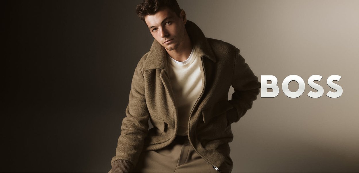 Jasnobrązowa kurtka z polaru z wyciętym kołnierzem, przednimi kieszeniami i prążkowanymi mankietami. W zestawie z białą koszulką z okrągłym dekoltem i beżowymi spodniami.