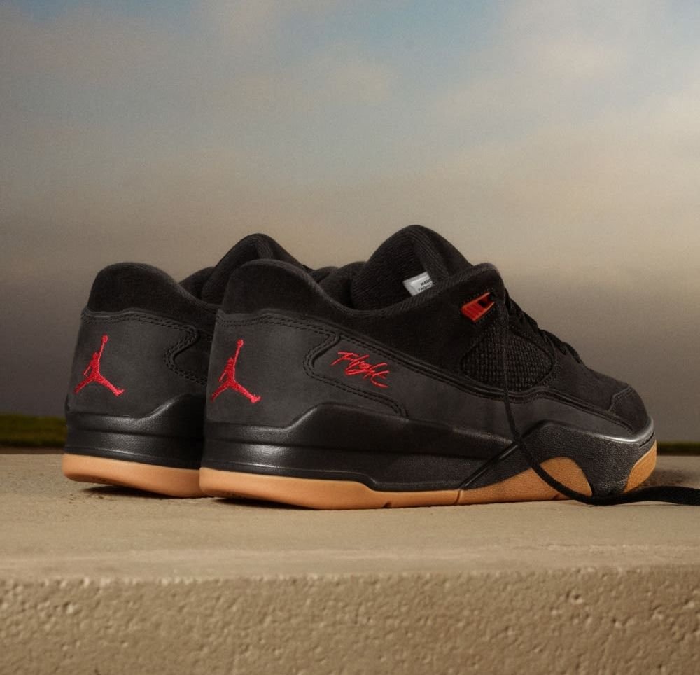 Baskets noires avec tige en daim, accents rouges, semelle en caoutchouc naturel et détails en maille. Présente le logo Jordan et l'inscription "Flight" sur le talon.