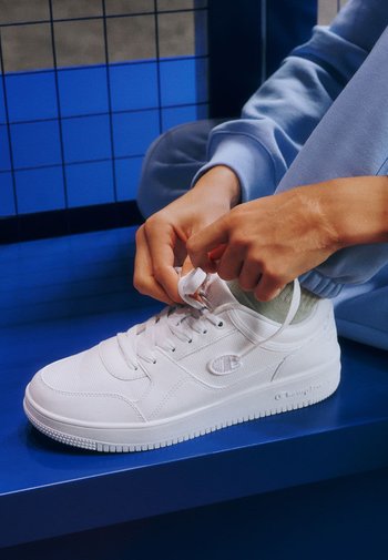 Weiße Sneaker mit strukturiertem Obermaterial, runden Zehen und klassischer Schnürung. Mit einem Logo an der Seite und einer dicken, gerippten Sohle.